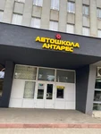 Центральний вхід до ужгородського відділення автошколи «Антарес» — фасад будівлі зі скляними дверима та банкоматом поруч.